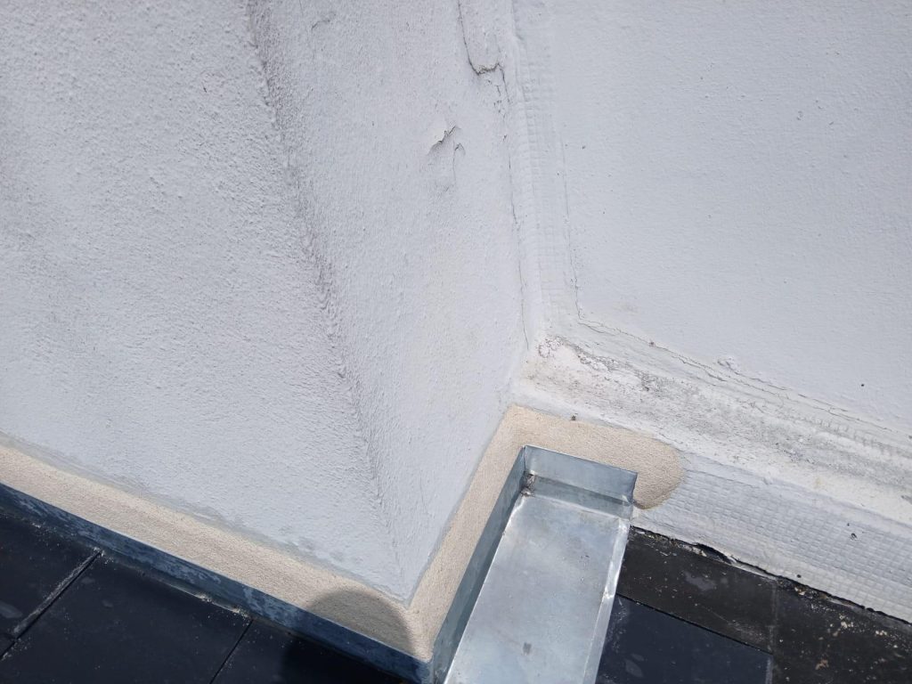 Détail photographié de raccords métalliques au pied d’un mur, fourni par MTI.